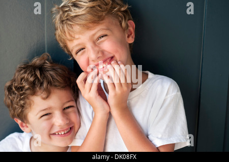 Zwei kaukasischen jungen Alter eine drei und eine Alter fünf, stehen vor einer blauen Wand. Sie sind beide tragen weiße T-shirts. Stockfoto