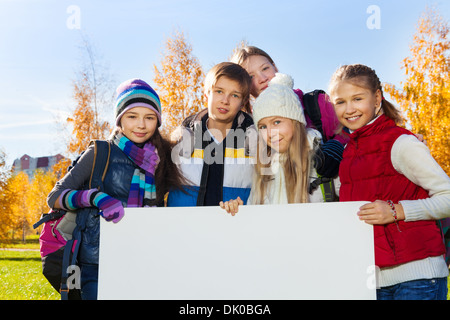 Enge Porträt Gruppe glücklich Teen Kids stehen im Herbst Park mit leeren weißen Tafel Plakat für das Hinzufügen von text Stockfoto