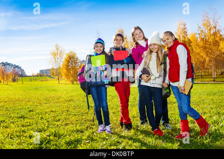 Gruppe von fünf Teen Kinder stehen im Herbst Park an sonnigen Tag mit Büchern, Dokumenten und gadgets Stockfoto