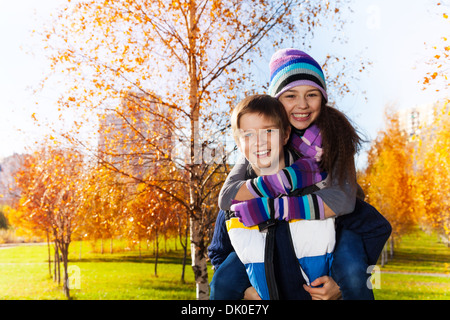 Glücklich und lachend 10 und 11 Jahre alt paar Schulkinder, junge ein Mädchen in warme Herbst Kleidung im park Stockfoto