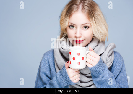 Porträt der blonden Schönheit in Winterkleidung halten Tasse Heißgetränk. Stockfoto