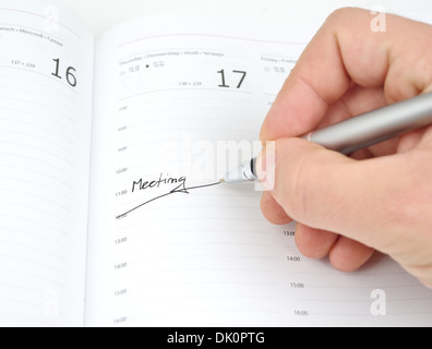 Hand mit Stift schreibt Stunden-Sitzung in der Kalender-Zeitplan Stockfoto