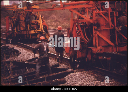 SÜDBAHN VORFAHRTSRECHT ARBEITER UND MASCHINEN. DIE MASCHINE BUCHSEN AUF DEN SCHIENEN, ZIEHT DIE ALTEN SCHWELLEN UND... 556901 Stockfoto