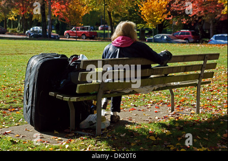 Obdachlose ältere Frau auf einer Parkbank mit ihren Habseligkeiten, Vancouver, BC, Kanada Stockfoto