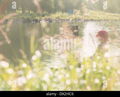Lebensstil Augenblick Sommer Kindheit. Kleines Mädchen sitzt am Steg durch Kanal, Schweden Stockfoto
