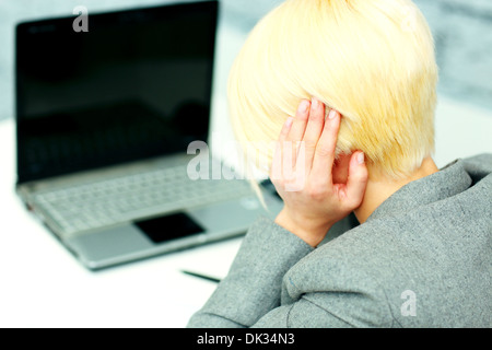 Junge Geschäftsfrau mit Kopfschmerzen an ihrem Arbeitsplatz im Büro Stockfoto