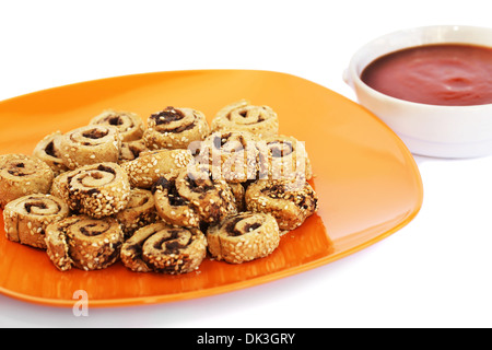 Zwieback mit Sesam, Oliven auf orange Teller und roter Soße isoliert auf weißem Hintergrund. Stockfoto