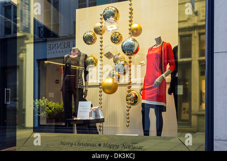 Weihnachtsschmuck im Schaufenster der Kleidung aufbewahren zeigen festliche Kleider in Einkaufsstraße im winter Stockfoto