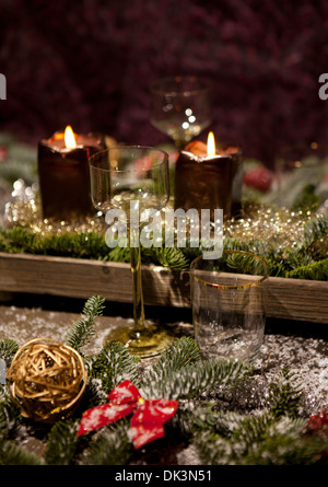 Weihnachten-Gedeck mit Kerzen, Weingläser auf dem Tisch, Kiefer-Äste sind geschmückt mit dekorativen Schnee Stockfoto