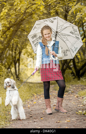 Lächelnd Fashionista posiert mit Hund im park Stockfoto