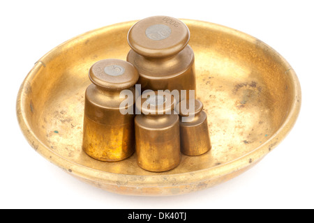 Vier alte Messing-Gewichte auf einem goldenen Teller Stockfoto