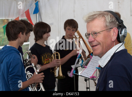Mann mittleren Alter tragen Kopfhörer steht vor Teenager junge Männer ein Messing-Quartett. Stockfoto