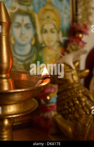 Eine beleuchtete Messing Lampe vor einem Porträt der Hindu-Götter Stockfoto