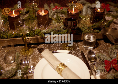 Weihnachten-Gedeck mit Kerzen, Weingläser auf dem Tisch, Kiefer-Äste sind geschmückt mit dekorativen Schnee Stockfoto