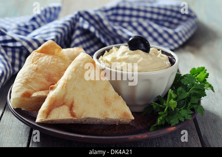 Schüssel mit frischen Hummus mit Olivenöl und Brot Scheiben auf hölzernen Hintergrund Stockfoto