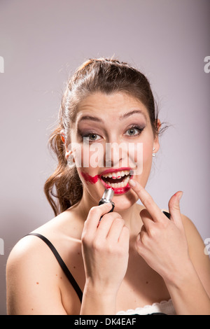 Junge Frau schmiert Lippenstift auf ihrem Gesicht Stockfoto