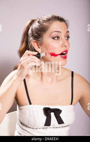 Junge Frau schmiert Lippenstift auf ihrem Gesicht Stockfoto