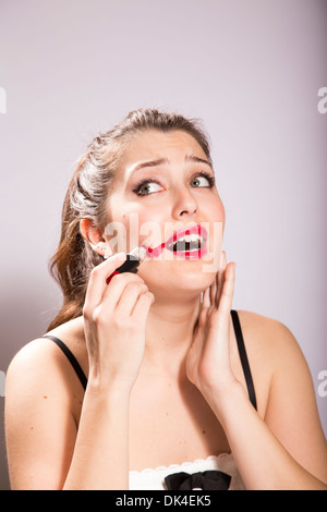 Junge Frau schmiert Lippenstift auf ihrem Gesicht Stockfoto