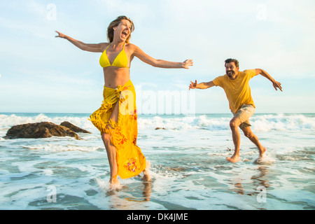 Mann jagt Frau am Strand Stockfoto