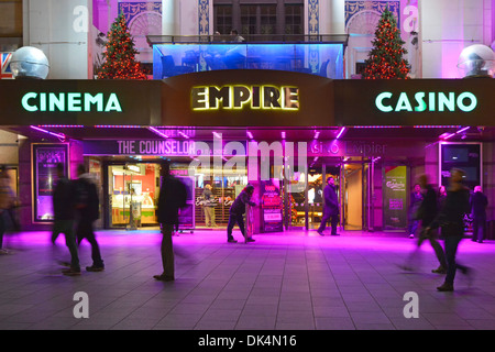 Abends Blick auf die Menschen auf dem Bürgersteig vor dem Empire Leicester Square Kino Casino Unterhaltungsgelände, in leuchtenden Farben, Flutlicht London England Großbritannien Stockfoto