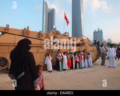 Abu Dhabi. 2. Dezember 2013. Kinder posieren für Fotos vor einem bewaffneten Fahrzeug unterliegt die Streitkräfte der Vereinigten Arabischen der Emirate (VAE) während einer militärischen Show präsentiert durch die Streitkräfte der VAE die 42. Nationalfeiertag der VAE in Abu Dhabi, VAE, 2. Dezember 2013 feiern. (Xinhua/Ma Xiping) Stockfoto