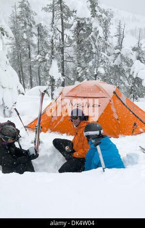 27. Februar 2011 - Missoula, Montana, USA - Sarah Ogburn (schwarze Jacke), Matt Cornette (blaue Jacke) und Pete Barrett (orange Jacke) haben einen Drink in ihrem Lager in einer Küche, die sie aus dem Schnee gegraben... Skifahrer-Camp und Ski im Hinterland von den Bitterroot Bergen von Montana. (Kredit-Bild: © Jed Conklin/ZUMAPRESS.com) Stockfoto