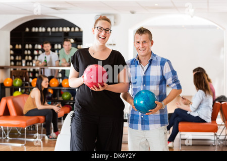 Glücklicher Mann und Frau mit Bowlingkugeln in Club Stockfoto