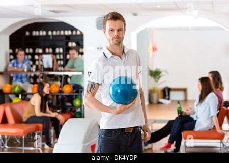 Zuversichtlich, junger Mann mit Bowling-Kugel im Club Stockfoto