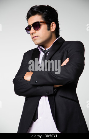 Indischen Jüngling in Jacke, Krawatte und Sonnenbrille mit verschränkten Armen Stockfoto