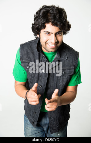 Lächelnde jungen indische Mann gekleidet in Jeans auf Kamera zeigen Stockfoto