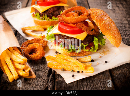 Big Burger in Brötchen mit Zwiebelringen und Pommes Frites. Selektiven Fokus auf dem burger Stockfoto