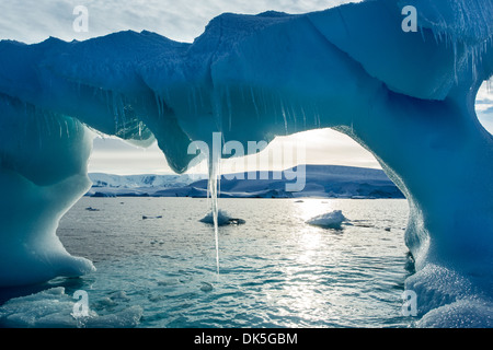 Antarktis, hängen Eiszapfen aus gewölbten Eisberg schwebt in der Nähe von Enterprise-Insel in der Wilhelmina Bay entlang der antarktischen Halbinsel in der Morgendämmerung Stockfoto