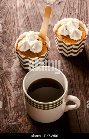 Black Coffee mit Cupcakes auf Holztisch. Stockfoto