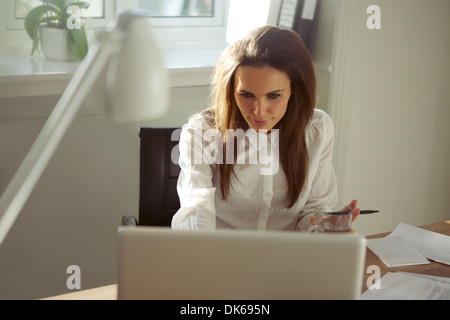 Junge Geschäftsfrau auf Laptop-Computer arbeiten. Schöne kaukasischen weibliche Führungskraft sitzen am Schreibtisch in ihrem Büro zu Hause. Stockfoto