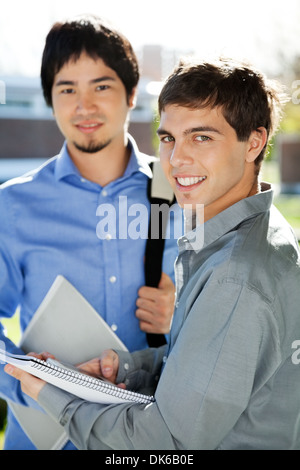 Männliche Schüler mit Büchern stehen im Campus der Universität Stockfoto