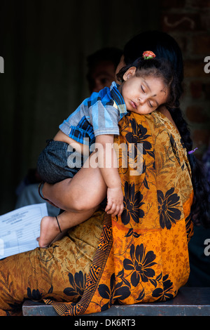 Junge indische Babymädchen schläft auf die Schulter Mütter in einem indischen Dorf. Andhra Pradesh, Indien Stockfoto