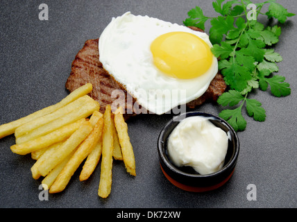 Viel Glück Steak. Sandwich Rumpsteak garniert mit einer Reihe kostenloser Spiegelei, eine Seite von Pommes Frites und Mayo. Stockfoto