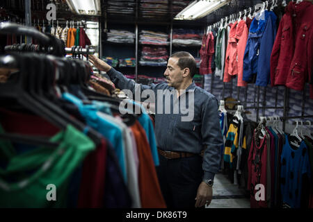 Kairo, Ägypten. 3. Dezember 2013.  Salesclerk Ali (R) ordnet Kleidung in einem Tuch-Shop in der Nähe von Tahrir-Platz. Ali arbeitet für den 21 Jahre alten Tuch Shop seit 6 Jahren er die Geschäft Turbulenzen während der inländischen politischen Veränderungen erlebt hat. Er räumt ein, dass der Shop-Betreiber Mohamed derzeit hat Mitarbeiter Gehalt aus seiner eigenen Tasche und Wirtschaft Zahlen seit 2011 stark betroffen ist. Der Laden hatte am 15:00 auf Dec.1 geschlossen werden, die die goldene Zeit zum Einkaufen genutzt. © Xinhua/Alamy Live-Nachrichten Stockfoto