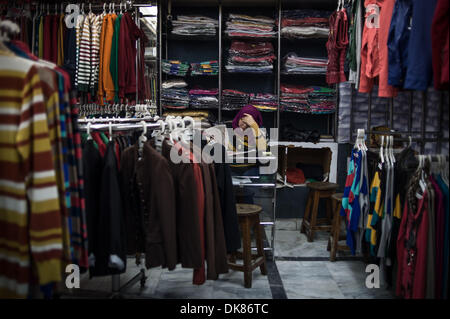 Kairo, Ägypten. 3. Dezember 2013.  Salesclerk Ali (R) ordnet Kleidung in einem Tuch-Shop in der Nähe von Tahrir-Platz. Ali arbeitet für den 21 Jahre alten Tuch Shop seit 6 Jahren er die Geschäft Turbulenzen während der inländischen politischen Veränderungen erlebt hat. Er räumt ein, dass der Shop-Betreiber Mohamed derzeit hat Mitarbeiter Gehalt aus seiner eigenen Tasche und Wirtschaft Zahlen seit 2011 stark betroffen ist. Der Laden hatte am 15:00 auf Dec.1 geschlossen werden, die die goldene Zeit zum Einkaufen genutzt. © Xinhua/Alamy Live-Nachrichten Stockfoto