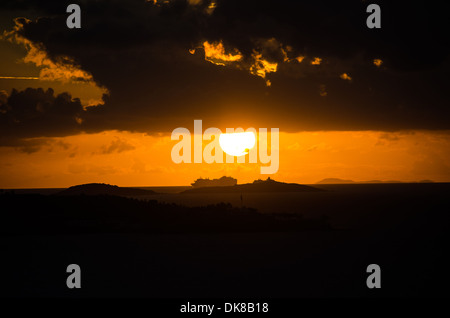 KARIBISCHES MEER – Ein dramatischer karibischer Sonnenuntergang färbt den Himmel in leuchtenden Orange- und Goldtönen. Stockfoto