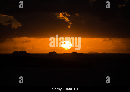 KARIBISCHES MEER – Ein dramatischer karibischer Sonnenuntergang färbt den Himmel in leuchtenden Orange- und Goldtönen. Stockfoto