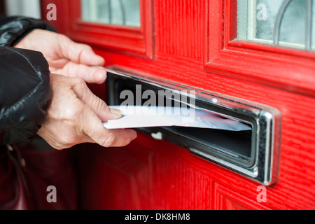 Hand einen roten Briefkasten Brief ins. Stockfoto