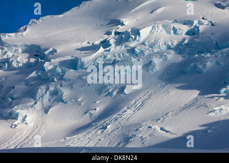 Antarktis, Anvers Island, Einstellung Sonne leuchten zerbrochene Oberfläche des Gletschers unter Berggipfeln Neumayer Kanal entlang Stockfoto