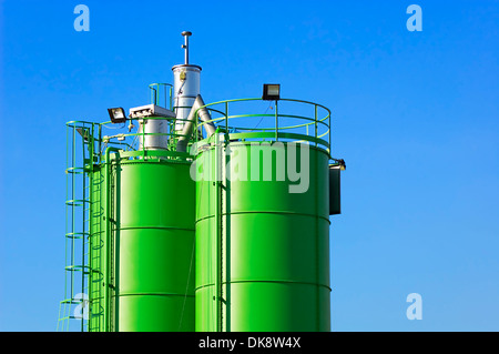 Zwei grüne Silos gegen blauen Himmel in einer Baustelle Stockfoto
