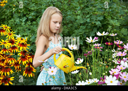 Kleines Mädchen Blumen im Garten gießen Stockfoto