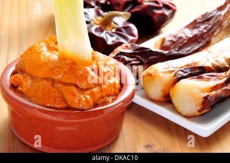 Nahaufnahme einer Platte mit gegrilltem Calcots, süße Zwiebeln und eine Schüssel mit Romesco-Sauce, typisch für Katalonien, Spanien Stockfoto