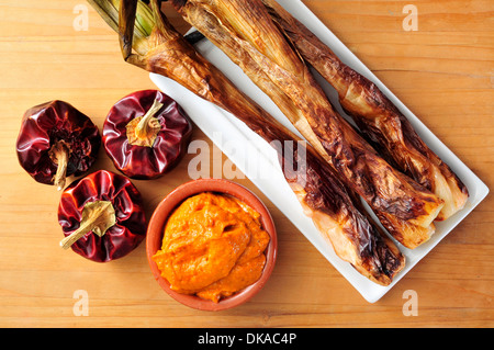 Nahaufnahme einer Platte mit gegrilltem Calcots, süße Zwiebeln und eine Schüssel mit Romesco-Sauce, typisch für Katalonien, Spanien Stockfoto