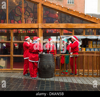 Nächstenliebe-Santa-Lauf in Liverpool Läufer entspannen auf dem Weihnachtsmarkt mit einem Bier Stockfoto