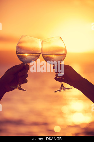 Mann und Frau klingende Weingläser mit Champagner bei Sonnenuntergang dramatischer Himmelshintergrund Stockfoto