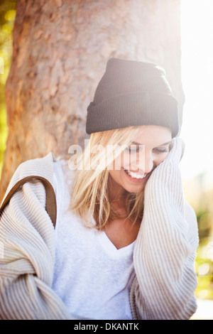 Junge Frau neben Baumstamm im park Stockfoto